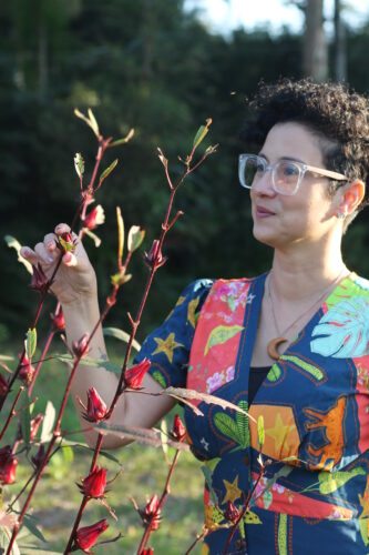 Marilua segurando ramos de hibisco, uma PANC muito últil e conhecida